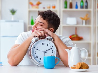 Çalar saati olan bir adam kahvaltıda uyuyakalıyor.