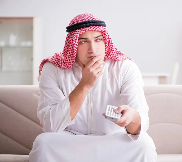 Young arab man watching tv sitting on the sofa — Stock Photo, Image