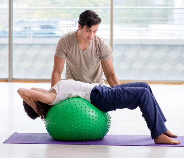 Personal Coach hilft Frau im Fitnessstudio mit Stabilitätsball — Stockfoto