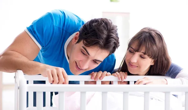 Jovem família feliz no berço da cama do bebê — Fotografia de Stock