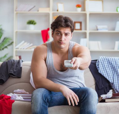 Genç adam dağınık bir odada çalışıyor.