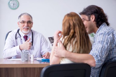 Genç çift yaşlı erkek doktoru ziyaret ediyor.