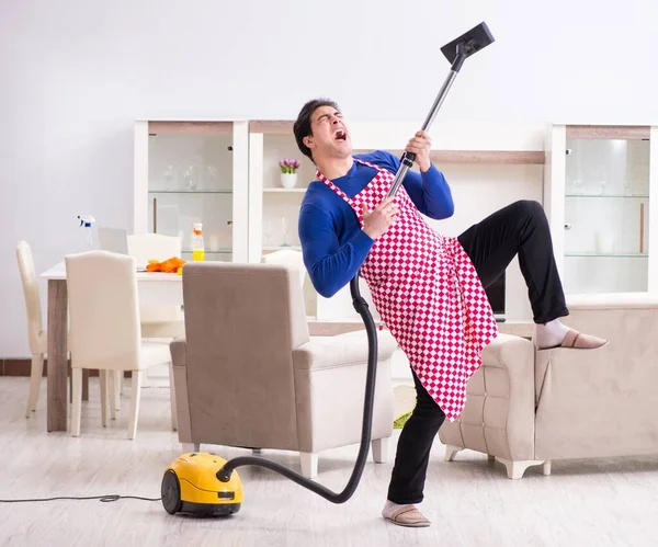 Jovem aspirador de pó limpeza seu apartamento — Fotografia de Stock