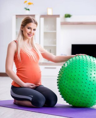 Evde doğum egzersizi yapmaya hazırlanan genç bir kadın.