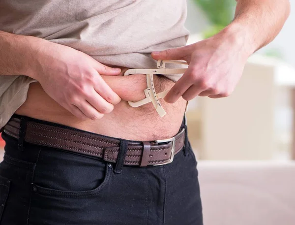 Hombre midiendo grasa corporal con pinzas — Foto de Stock