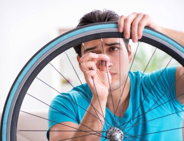 Evde bisiklet tamir eden genç bir adam.