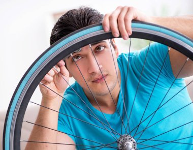 Evde bisiklet tamir eden genç bir adam.