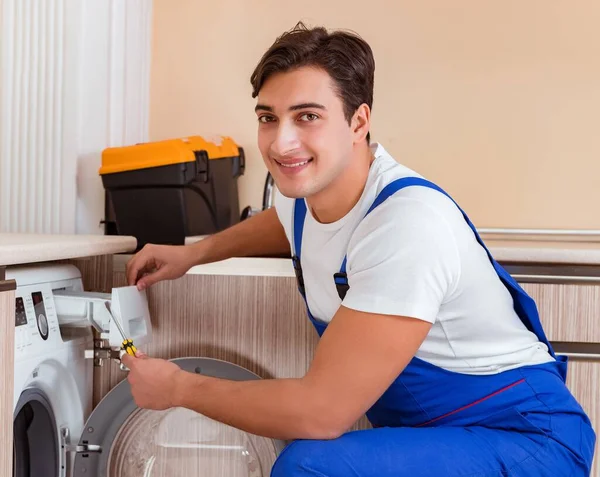 Repairman repairing washing machine at kitchen — Stock Photo, Image