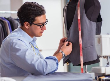 Genç terzi yeni elbiseler üzerinde çalışıyor.