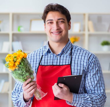 Çiçekçi asistanı bir demet çiçek veriyor.