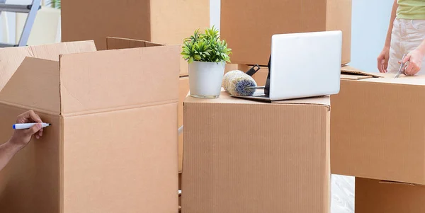 Familia joven desempacando en casa nueva con cajas —  Fotos de Stock