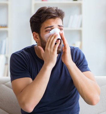 Genç adam estetik cerrahi burnundan sonra evde iyileşiyor.