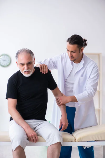 Vecchio ferito visitando giovane medico — Foto Stock