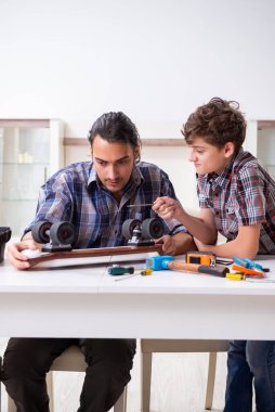 Genç baba oğluyla kaykay tamir ediyor.