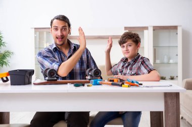 Genç baba oğluyla kaykay tamir ediyor.