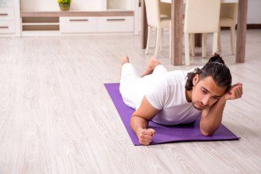 Genç adam evde fiziksel egzersiz yapıyor.