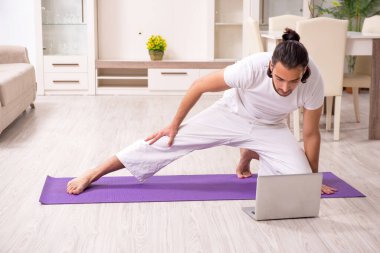 Genç adam evde fiziksel egzersiz yapıyor.