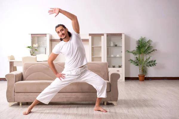 Jovem fazendo exercícios físicos em casa — Fotografia de Stock