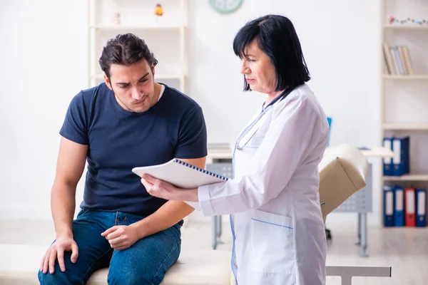 Ung manlig patient besöker äldre kvinnlig läkare — Stockfoto