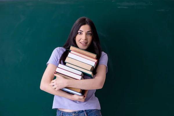 Ung kvinnlig lärare student framför green board — Stockfoto