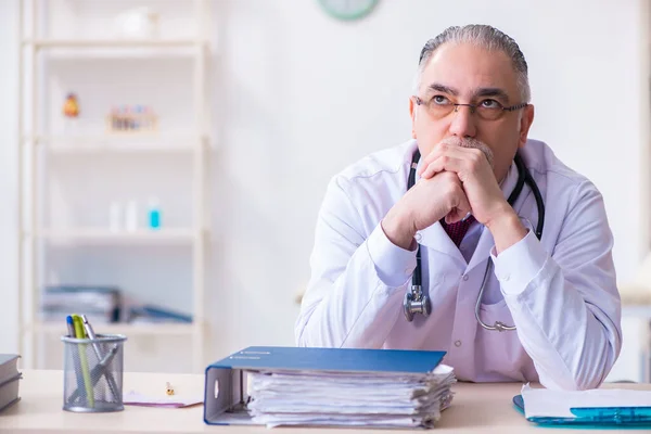 Oude mannelijke arts werkzaam in de kliniek — Stockfoto