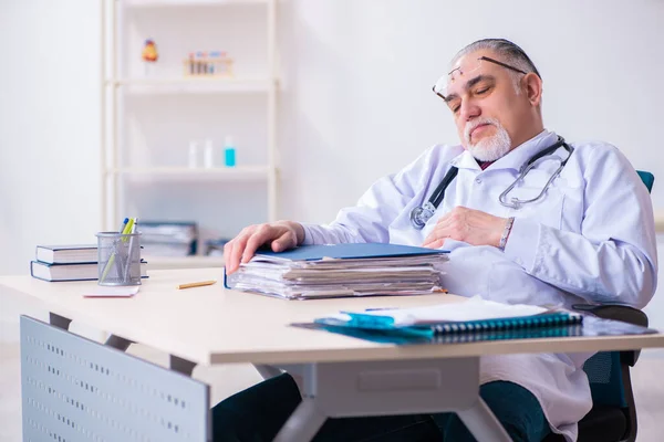 Old male doctor working in the clinic — Stock Photo, Image