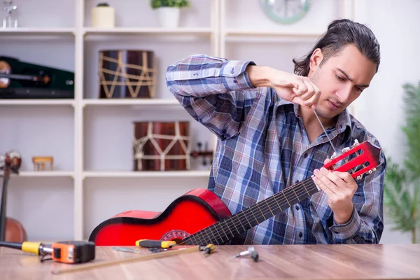 Mladý pohledný opravář opravy kytara — Stock fotografie