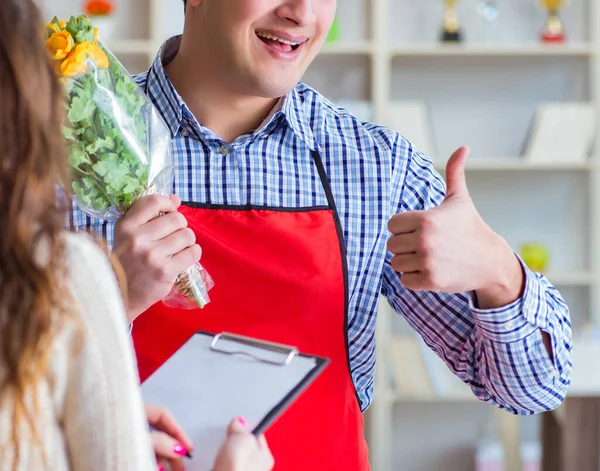 Asistente de floristería vendiendo flores a cliente femenino — Foto de Stock