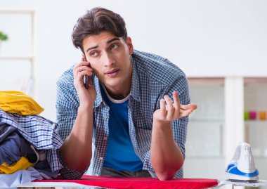 Genç adam evde çamaşır ütülüyor.