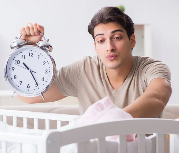 Papá joven con reloj cerca de la cuna recién nacida — Foto de Stock