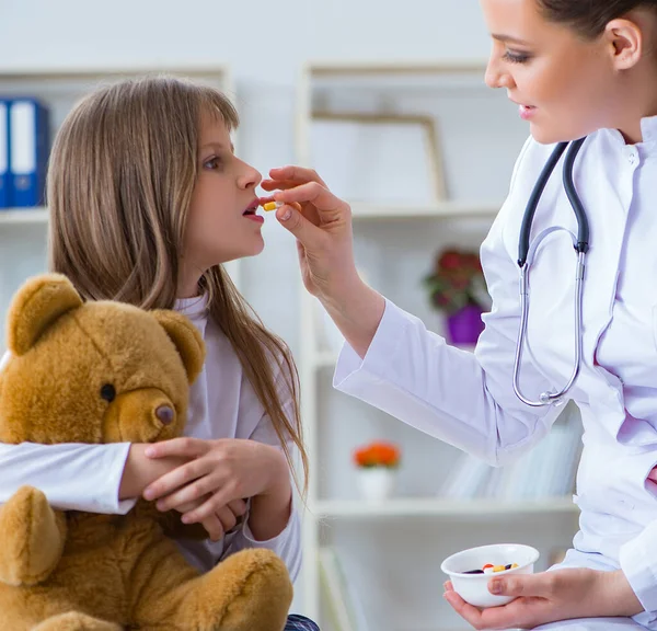 Mulher médica examinando pouco bonito menina com urso de brinquedo — Fotografia de Stock