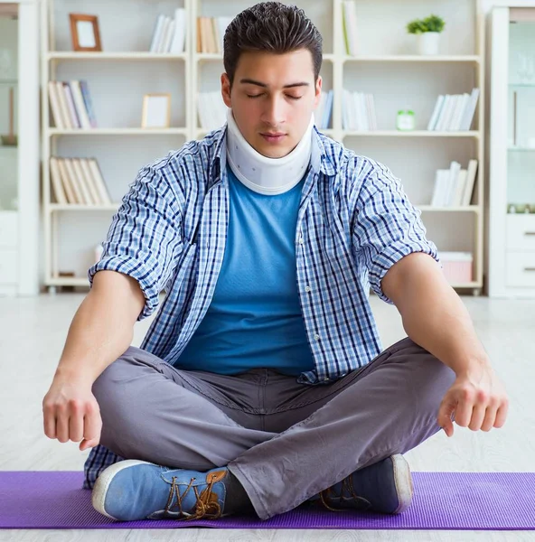 Hombre con lesión en el cuello meditando en casa en el suelo —  Fotos de Stock