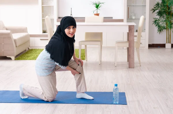 Jonge vrouw in hijab doet oefeningen thuis — Stockfoto