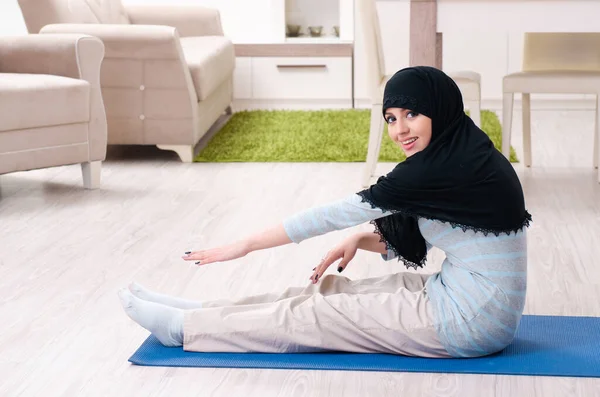 Jonge vrouw in hijab doet oefeningen thuis — Stockfoto