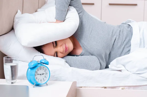 Mujer joven acostada en la cama en concepto de gestión del tiempo —  Fotos de Stock