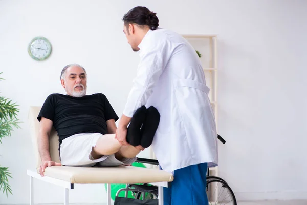 Oude gewonde man op bezoek bij jonge dokter — Stockfoto