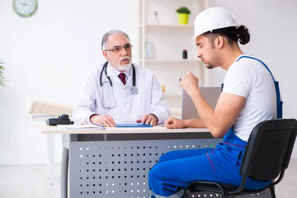 Young male contractor visiting old doctor