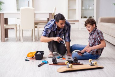 Genç baba oğluyla kaykay tamir ediyor.