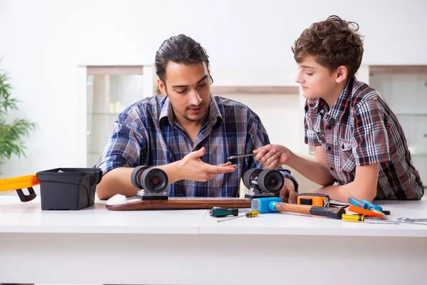 Genç baba oğluyla kaykay tamir ediyor.