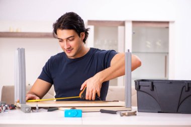 Evdeki mobilyaları tamir eden genç adam.