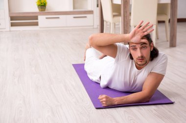 Genç adam evde fiziksel egzersiz yapıyor.