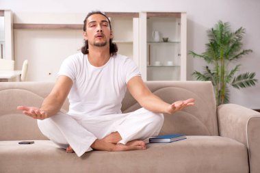 Genç adam evde fiziksel egzersiz yapıyor.