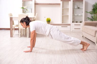 Genç adam evde fiziksel egzersiz yapıyor.