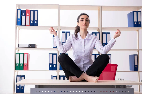 Young female employee doing exercises in the office