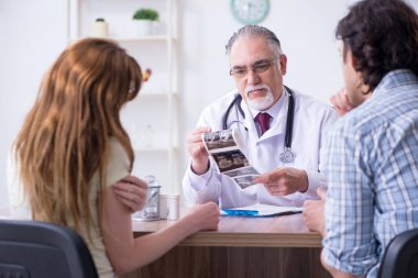 Genç çift yaşlı erkek doktoru ziyaret ediyor.