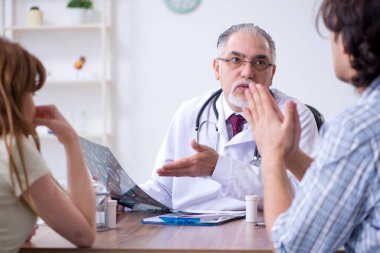 Genç çift yaşlı erkek doktoru ziyaret ediyor.