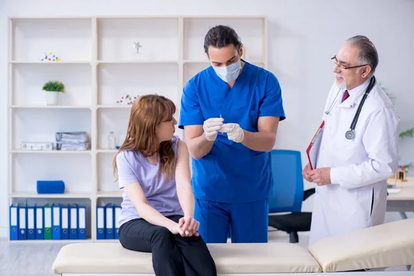 Twee artsen onderzoeken jonge vrouw — Stockfoto