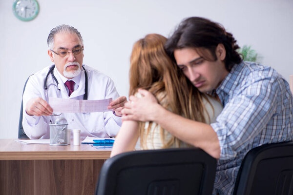 Молодая пара, посещающая пожилого врача