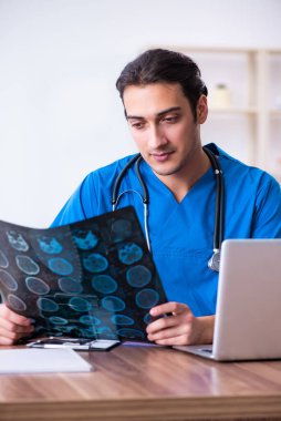 Genç erkek doktor röntgen görüntülerine bakıyor.