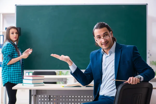 Jonge knappe leraar en vrouwelijke student in de klas — Stockfoto